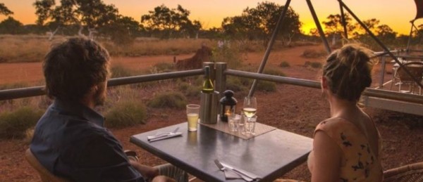 couple sitting on outdoor deck watching the sunset with a wine and beer at Karijini Eco Retreat